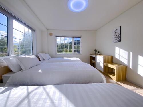 a white bedroom with two beds and windows at Niseko Powder fox in Kutchan