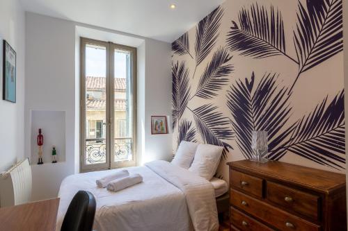 - une chambre avec un lit orné d'une fresque murale représentant des feuilles de palmier dans l'établissement Appartement T4 cours Julien proche Vieux-Port - parking gratuit, à Marseille