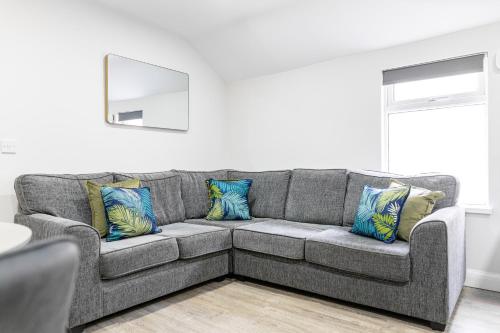 a gray couch with pillows in a living room at Modern Apartments Near Cardiff City Centre in Cardiff