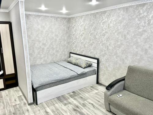 Un dormitorio pequeño con una cama y un sofá. en 1 комнатная квартира посуточно, en Uralsk