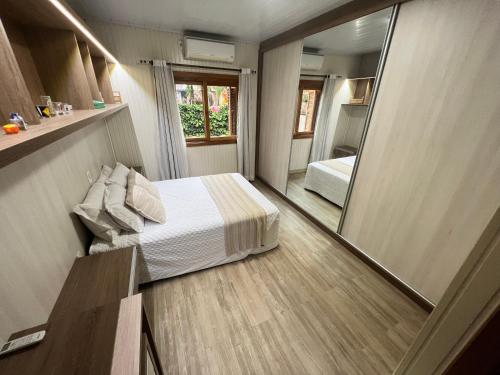 1 dormitorio con cama y espejo grande en Casa mais Central de Gramado en Gramado