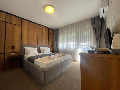 a bedroom with a large bed and a television at New Prishtina Luxury Rooms in Pristina