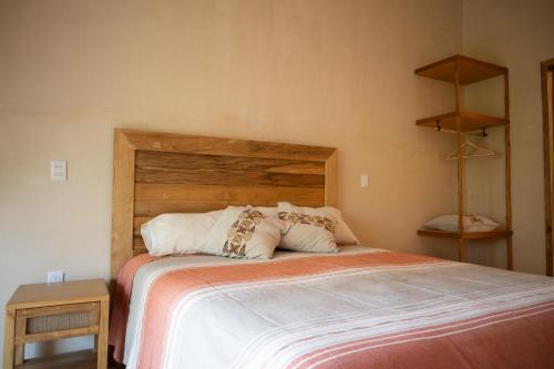 una camera con un grande letto con testiera in legno di Yax Kiin Casa Boutique a Puerto Morelos