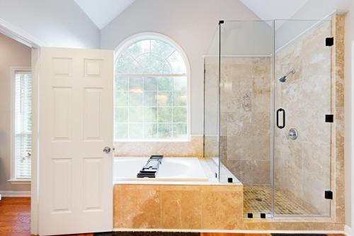 La salle de bains est pourvue d'une baignoire, d'une douche et d'une fenêtre. dans l'établissement Golden Acres Manor, à Atlanta