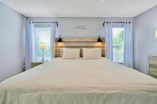 a bedroom with a large white bed with two windows at Stunning Family Retreat with Pool, Hot Tub, Patio, King Bed in Kissimmee