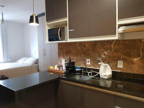 eine Küche mit einem Waschbecken und ein Bett in einem Zimmer in der Unterkunft Muito Conforto Selenita1 in Barueri