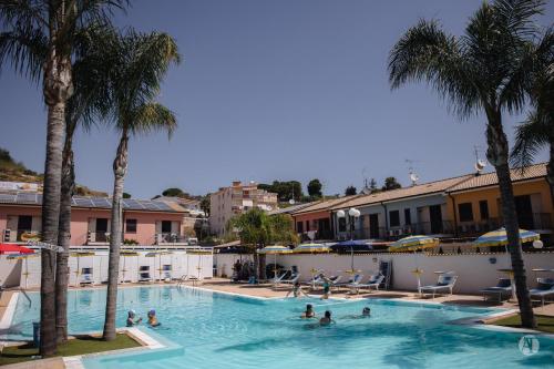 um grupo de pessoas numa piscina com palmeiras em Andrea Case Vacanze L'Ancora em Porto Empedocle