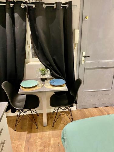 una pequeña mesa con sillas y una cortina negra en Studette cœur de ville, en Besançon