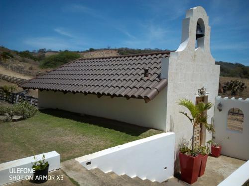 a white house with a brown tile roof at La Capilla tropical in Puerto de Luperon