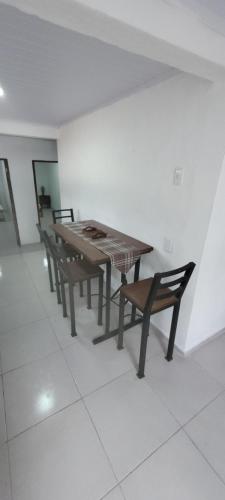 uma mesa e bancos numa sala com azulejos brancos em Apartamento Romian 2 em Paysandú
