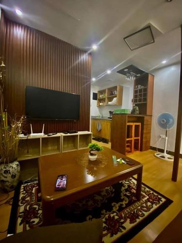 sala de estar con mesa de centro y TV de pantalla plana en Flores Staycation, en Marilao