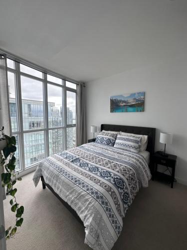 a bedroom with a bed and a large window at Stylish 2 Bedrooms Condo w/ awesome View & Parking in Toronto