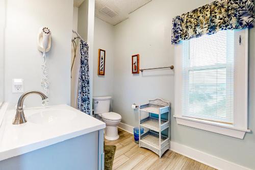 a bathroom with a sink and a toilet and a window at About the Waves in Avon