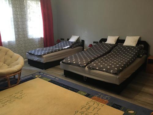 エゲルにあるMandula Vendégházのベッド2台、椅子、ラグが備わる客室です。
