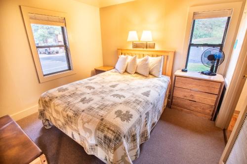 a small bedroom with a bed and two windows at Castle Mountain Lodge in Estes Park