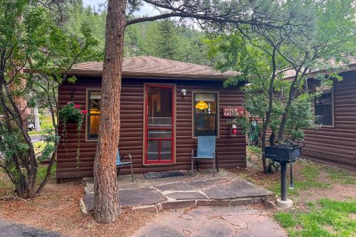 a log cabin with a red door and a tree at Castle Mountain Lodge in Estes Park