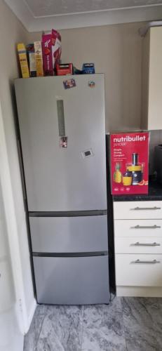 a refrigerator freezer sitting in a kitchen next to a dresser at Yvonnehut in Luton