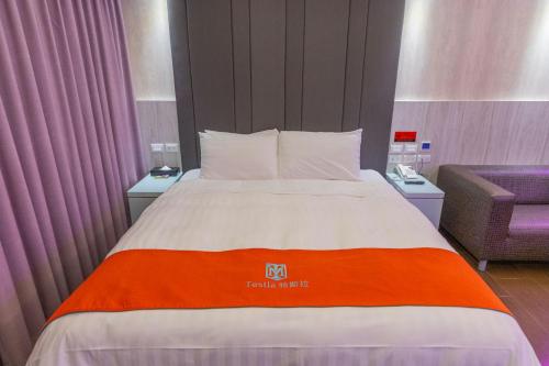 a bed in a hotel room with an orange and white blanket at King Motel王者 in Taoyuan