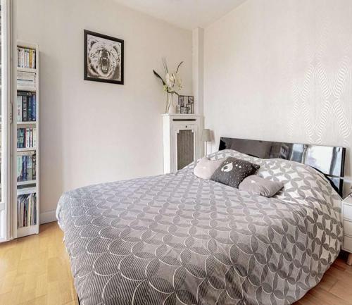 ein Schlafzimmer mit einem Bett mit einer grauen Bettdecke in der Unterkunft Appartement 2 chambres in Romans-sur-Isère