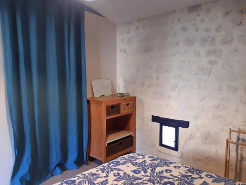 a bedroom with a bed and a blue curtain at Gîte VillaBoé in Villebois-Lavalette