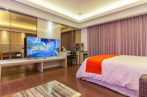 a hotel room with a bed and a flat screen tv at King Motel王者 in Taoyuan