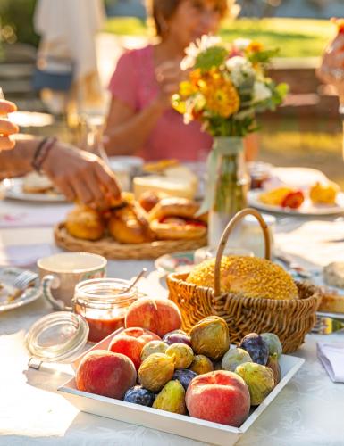 a table topped with plates of food and a basket of fruit at LE DOMAINE DE GORNETON in Chasse-sur-Rhône