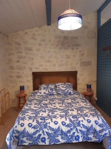 a bedroom with a bed with a blue and white comforter at Gîte VillaBoé in Villebois-Lavalette