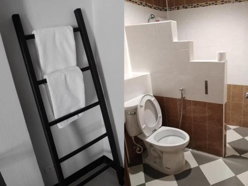 a bathroom with a toilet and towels on a shelf at กัญญ่า เพลส KANYA in Maha Sarakham