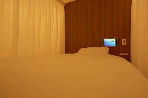 a bedroom with a bed and a tv on the wall at SLEEPLAB 高輪 -睡眠特化型Hotel- in Tokyo