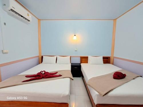 two beds in a room with red bows on them at Peace Lanta Mansion in Ko Lanta
