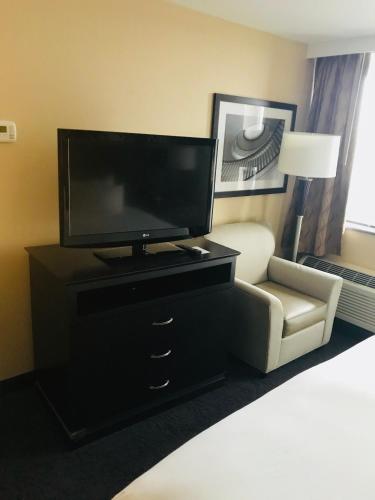 a bedroom with a tv and a couch and a chair at The Strathallan - a DoubleTree by Hilton in Rochester
