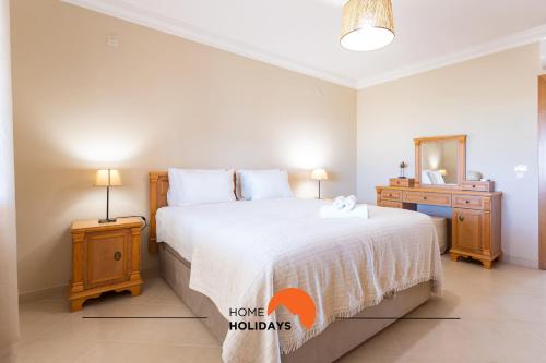 a bedroom with a bed and a dresser and a mirror at #130 Praia Village by Home Holidays in Vilamoura