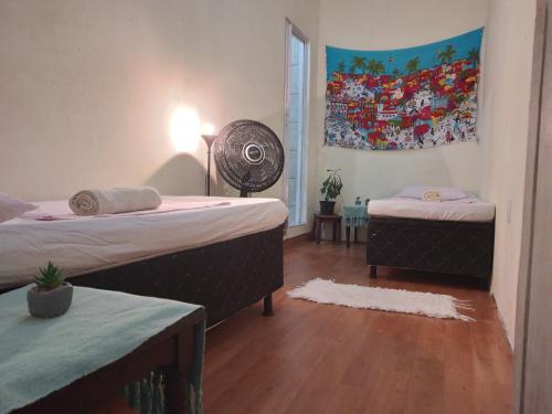 1 dormitorio con 2 camas y un cuadro en la pared en AXÉ HOME Martha & Jorge, en Salvador