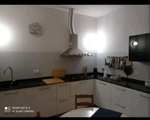 uma cozinha com armários brancos e um forno com placa de fogão em Casa Alessandro em Lucca