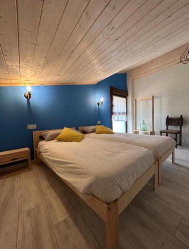 two beds in a bedroom with a blue wall at Casa Julita Etxea in Morentin