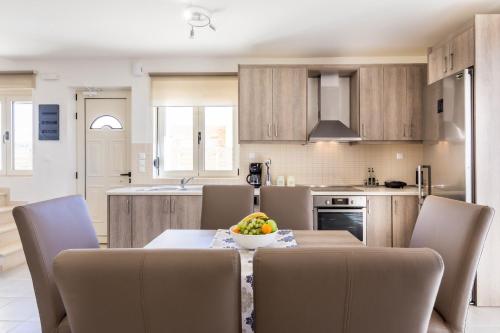 a kitchen with a table with chairs and a bowl of fruit at Blue Horizon Lefkopetra in Triopetra