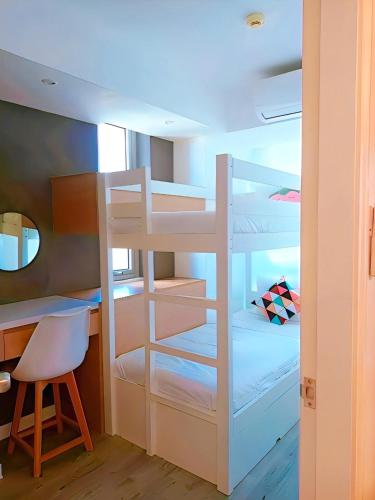 a bunk bed in a room with a desk and a chair at Holiday Escape Philippines in Manila