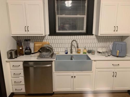 eine Küche mit weißen Schränken und einem Waschbecken in der Unterkunft Dr. Yaple's Art Deco House in Lafayette