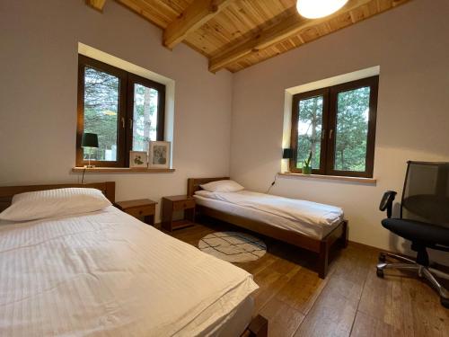 a bedroom with two beds and a desk and a chair at Zielono - domek na Roztoczu in AdamÃ³w