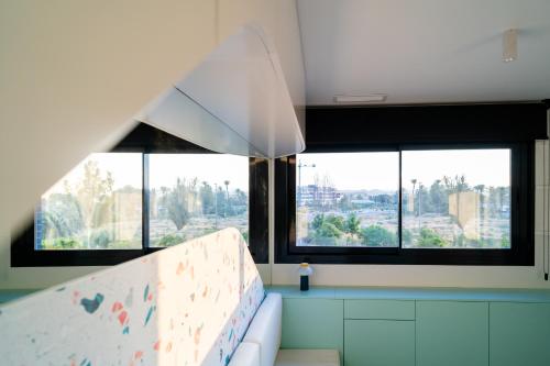 a room with two large windows and a white couch at Apartamento de diseño con piscina y gimnasio By ElConserje in Murcia