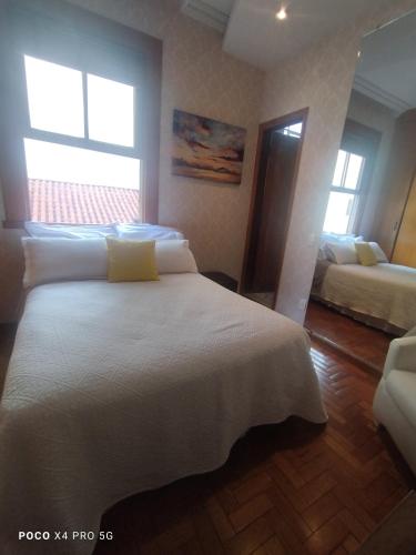 a bedroom with a large white bed and two windows at Quarto Suite - SAVASSI BH in Belo Horizonte