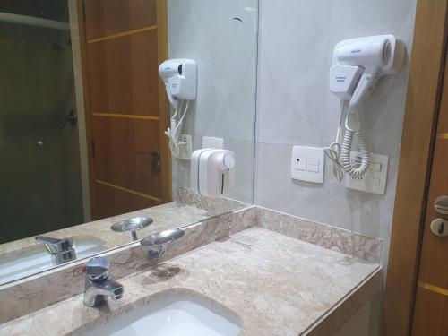 a bathroom sink with two hair dryers and a mirror at Apto no Comfort Suites COM CAFÉ E ESTAC Incluso in Barueri