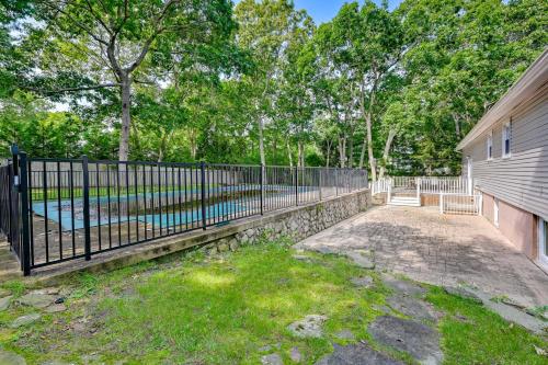 a fence in front of a yard with a pool at Hampton Bays Retreat Walk to Squires Beach! in Hampton Bays