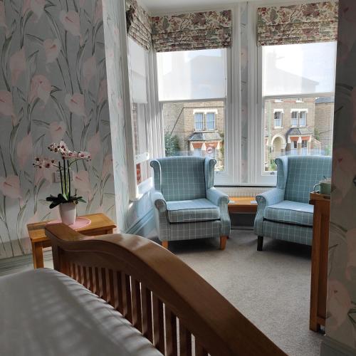 a bedroom with two chairs and a bed and a window at The Corner House in Lowestoft