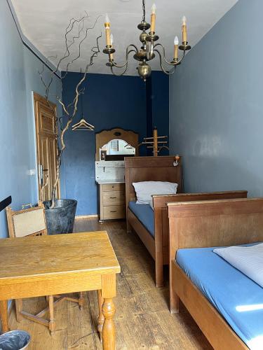 ライプツィヒにあるホームプラネット ホステルの青い壁のベッドルーム1室(テーブル、ベッド2台付)
