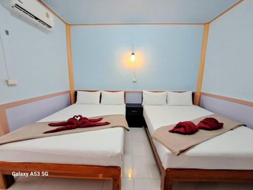 two beds in a room with red pillows on them at Peace Lanta Mansion in Ko Lanta