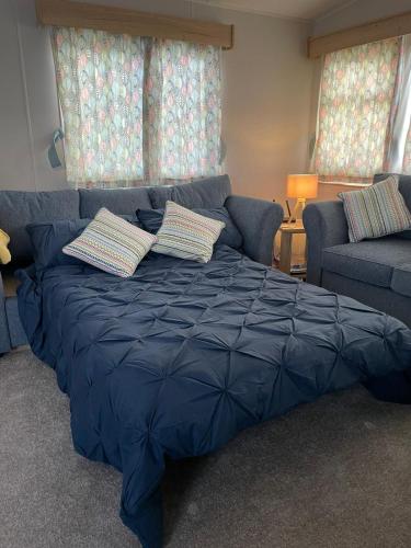 a blue bed in a living room with a couch at Golden Palm Resort - The Adelaide - Coastal Caravan Breaks in Skegness