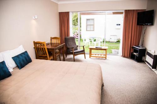 a hotel room with a bed and a table and chairs at Alpenhorn Motel in Te Anau