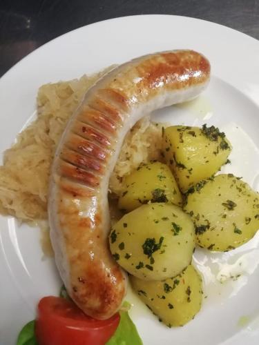 a plate of food with a sausage and potatoes at Landgasthof Santner in Thalgau