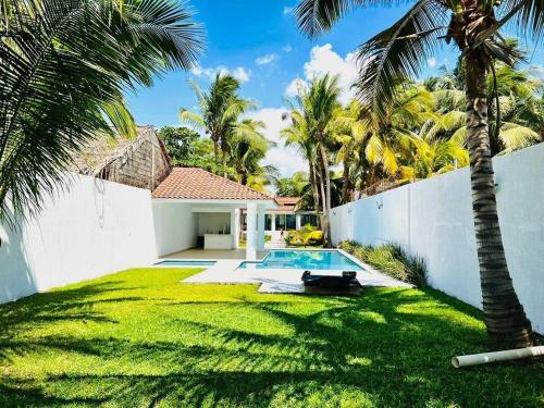 a backyard with a swimming pool and palm trees at Casa Trébol: Tu Casa de Playa. Disfruta en familia in Puerto Arista